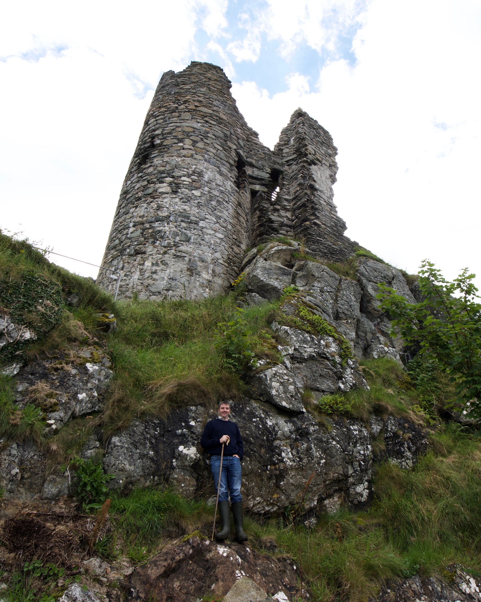A man with a dog in front of the imposing Castle Sween ruin