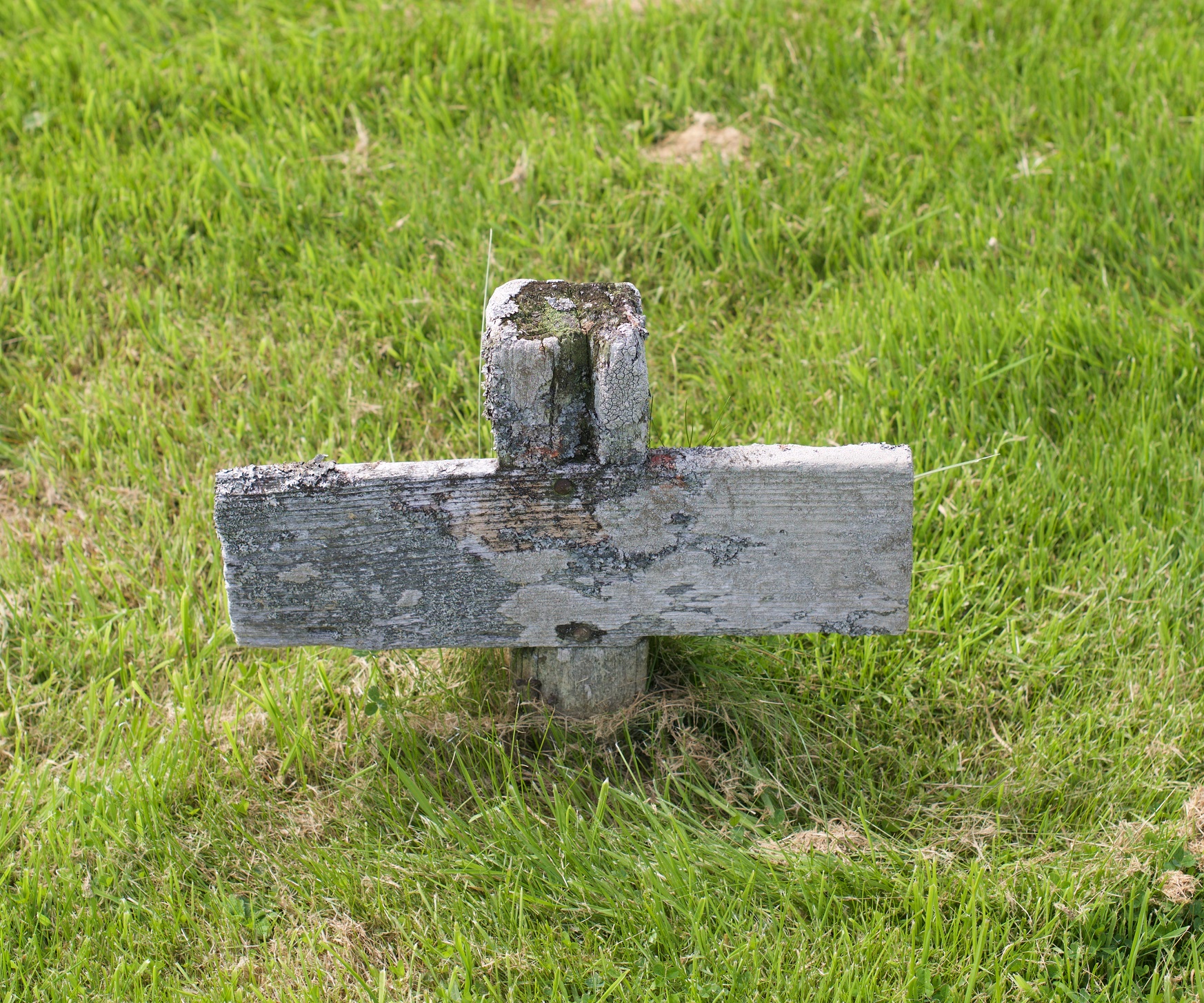 a wooden cross on grassy ground