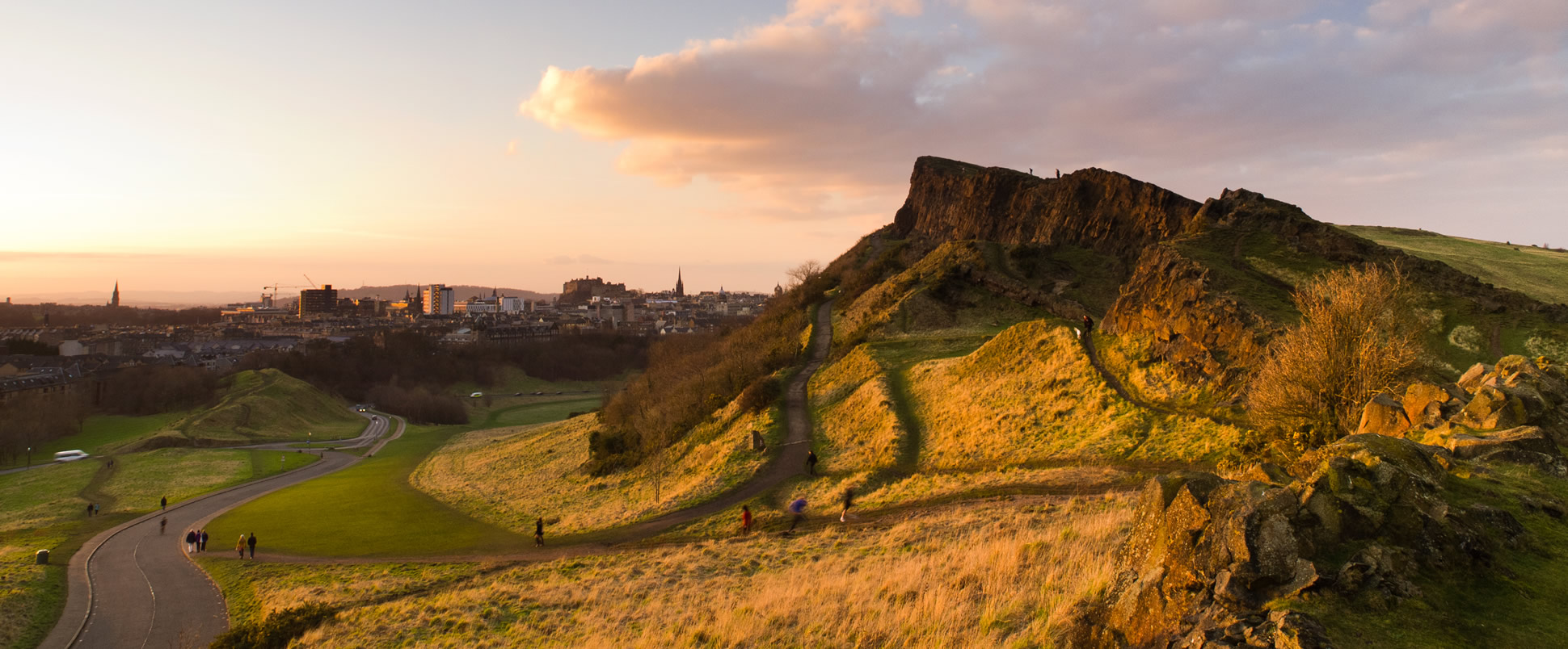 A picture of members of the public enjoying Holyrood Park at dusk.