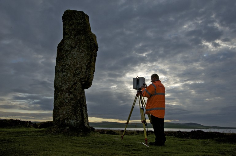 Man in orange hi-vis coat laser scanning ring of brodgar