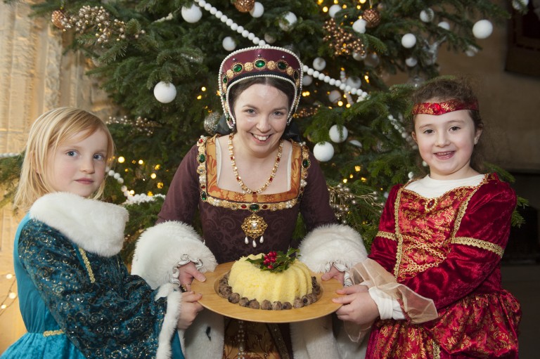 A costumed performer and two little girls show off a cake