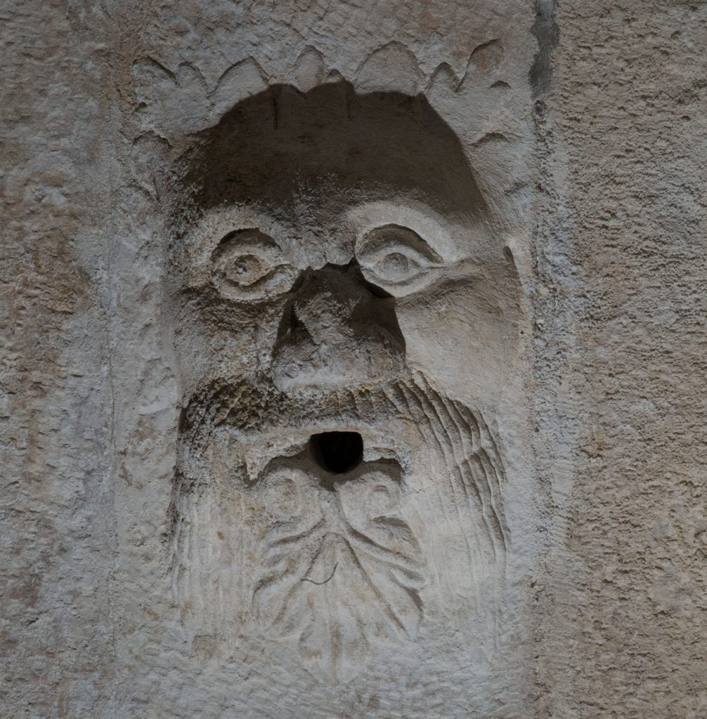 A photograph of a stone carving of a man's face with a beard