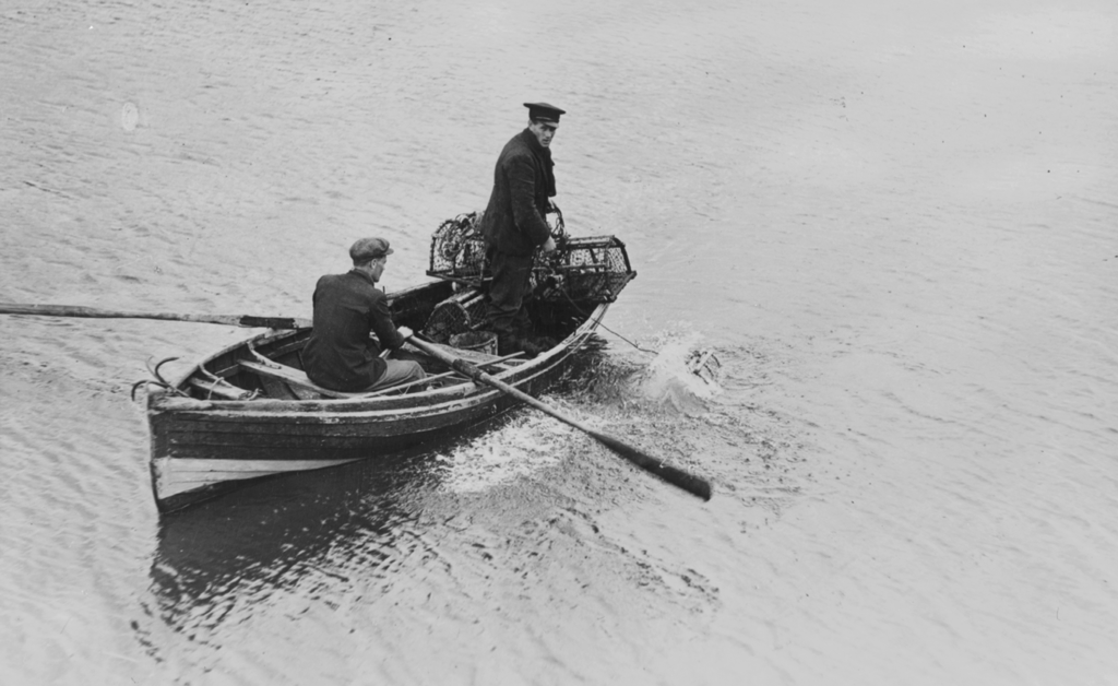 A black and white photograph of two men in a rowing boat on the water.