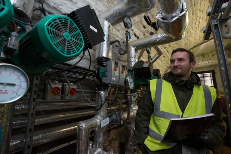 man in hi-vis vest examines a newly installed boiler designed to lower carbon emissions