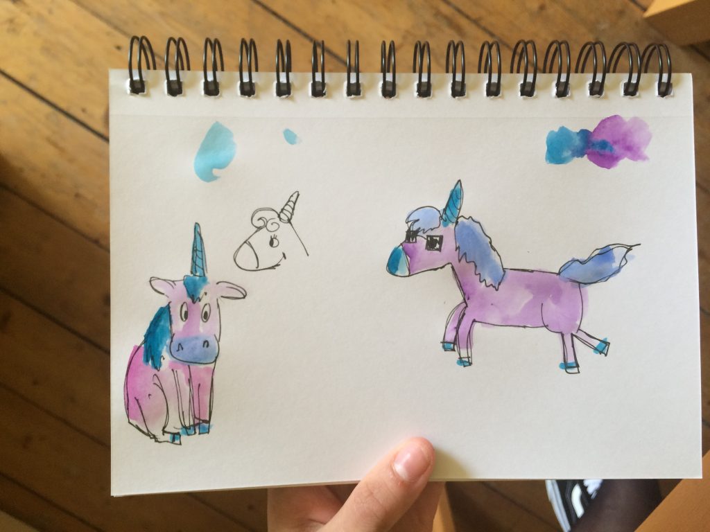 page in a sketchbook showing different sketches of a unicorn