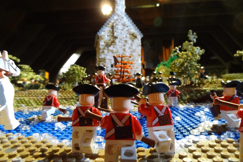 three lego figures facing away from camera as if charging towards castle in the background