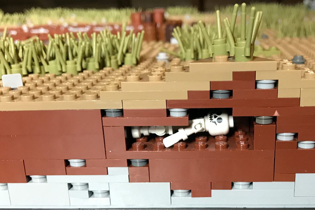 cross section of a lego model showing a lego skeleton buried beneath layers of plastic soil