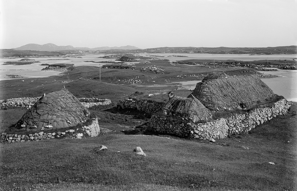 black and white photograph of thatched buildings on a remote island