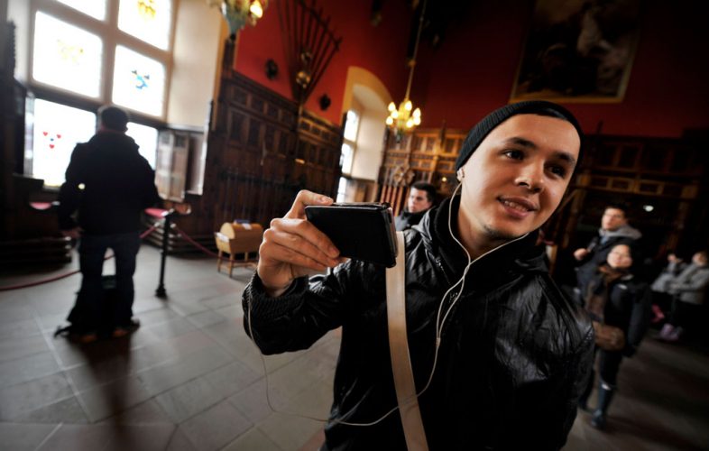 Image of a young person visiting Edinburgh Castle taking photos with his smartphone