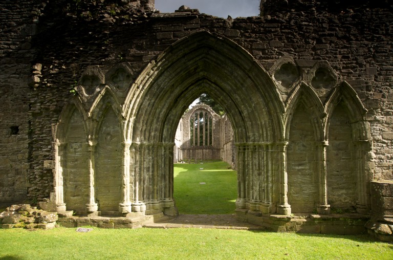 stone arch leading to a wooden door in the distance