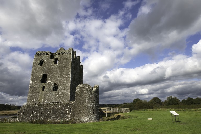 square tower with remains of curtain wall and green grass in foreground
