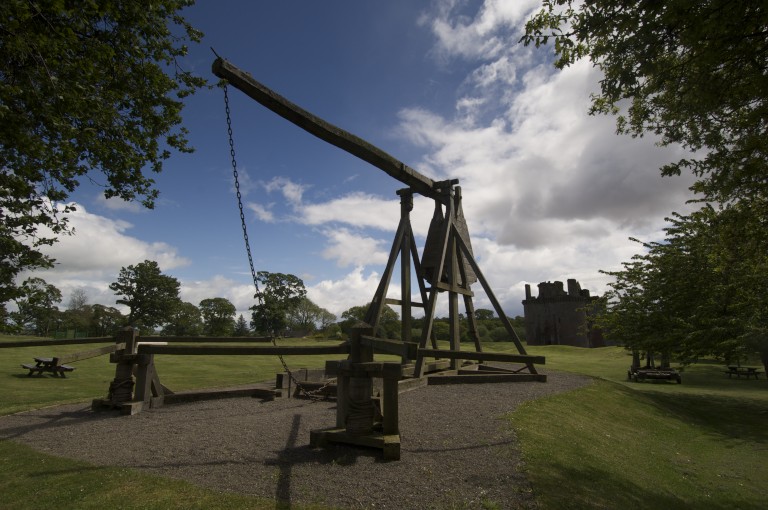 wooden trebuchet siege engine with long boom forming the arm and a counterweight 