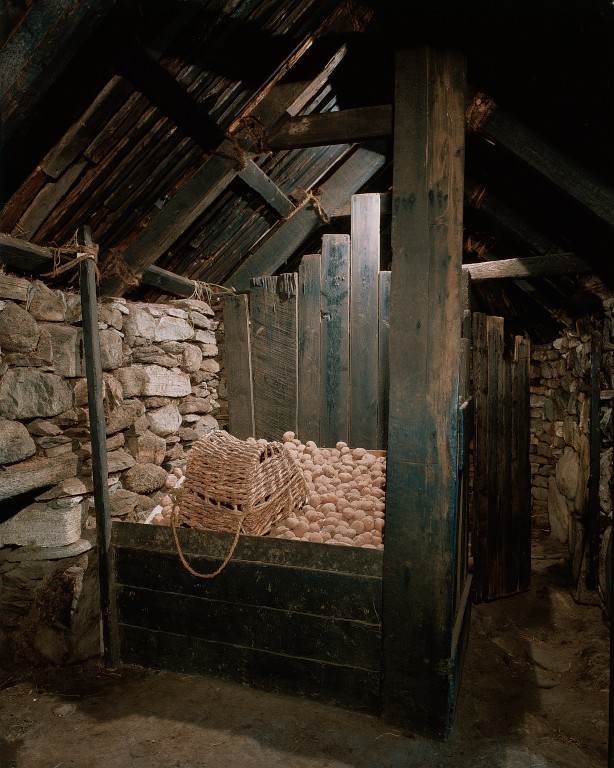 brick building with wooden box full of potatoes with a wicker basket on top