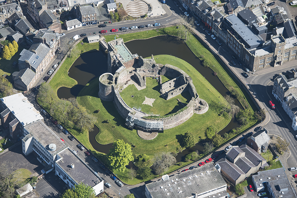 aerial view of a round castle wall with a moat around the outside in the centre of a town