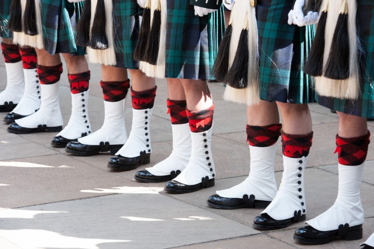 close up of 6 pairs of legs wearing army uniform socks, kilts and shoes 