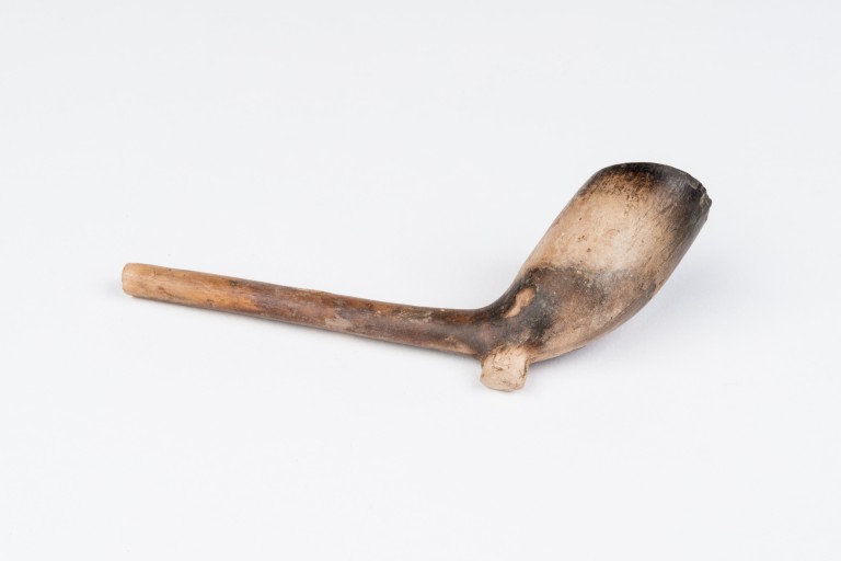 clay smoking pipe on a white surface 