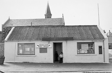 Black and white photo from the 1970s shows children lurking in the doorway of a post office