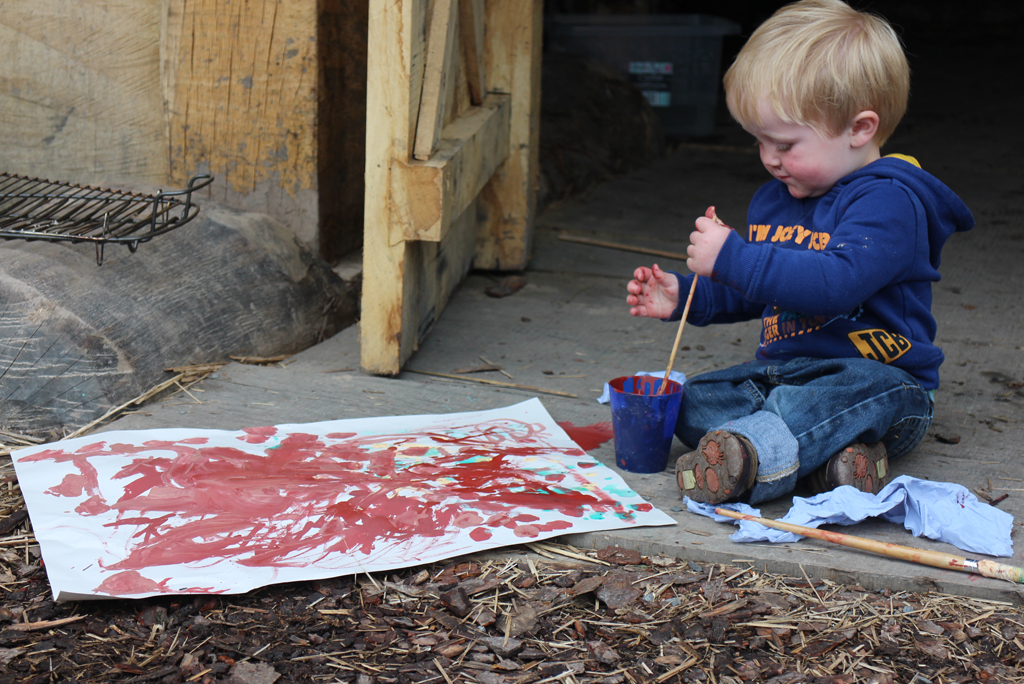 small child sitting on the ground doing a painting