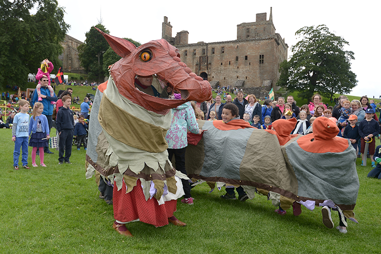 People watching performers in a medieval-looking dragon costume