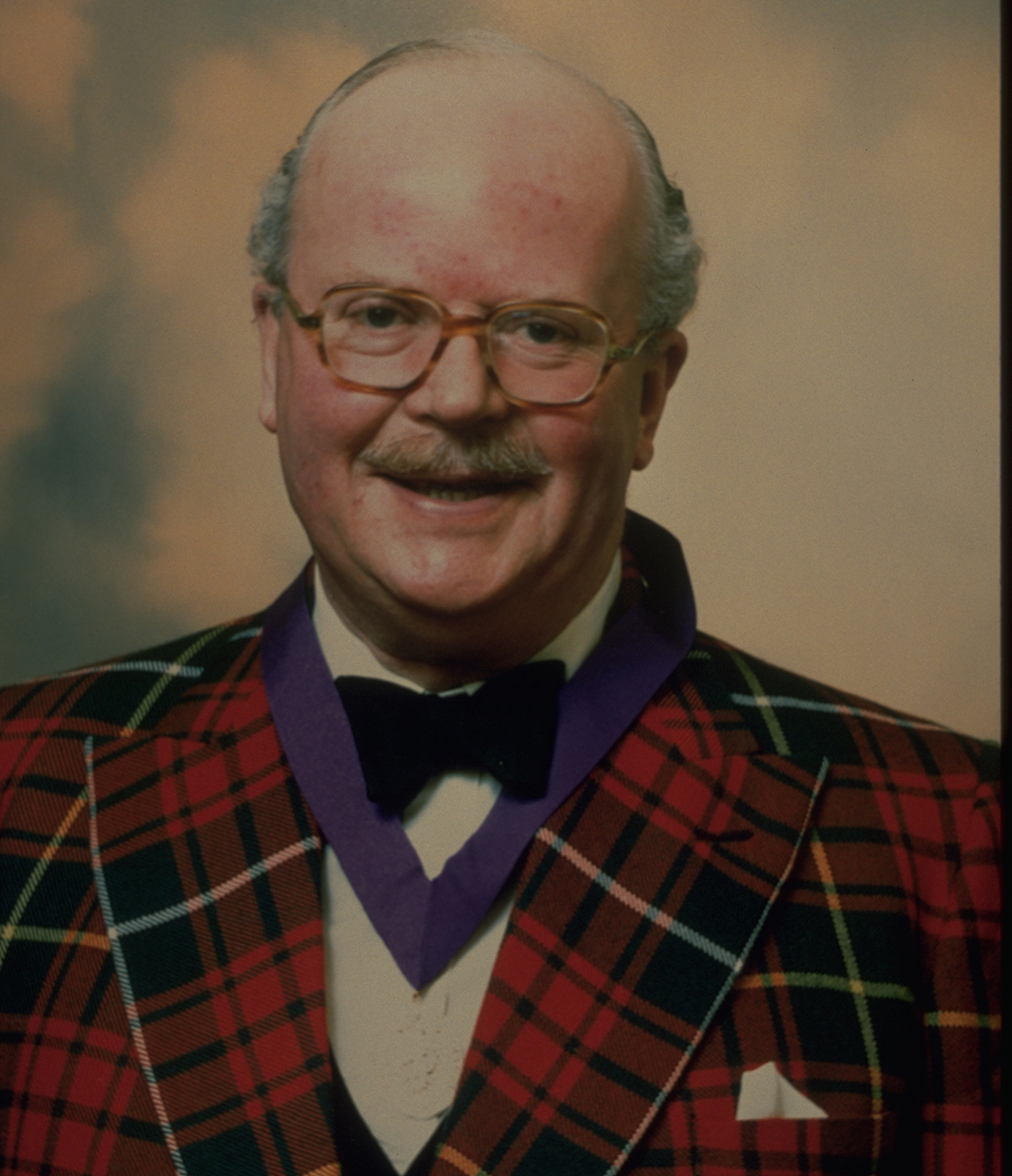 head and shoulders of man in tartan jacket smiling at camera
