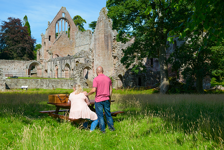 View of Dryburgh Abbey with a couple sitting at a picnic bench