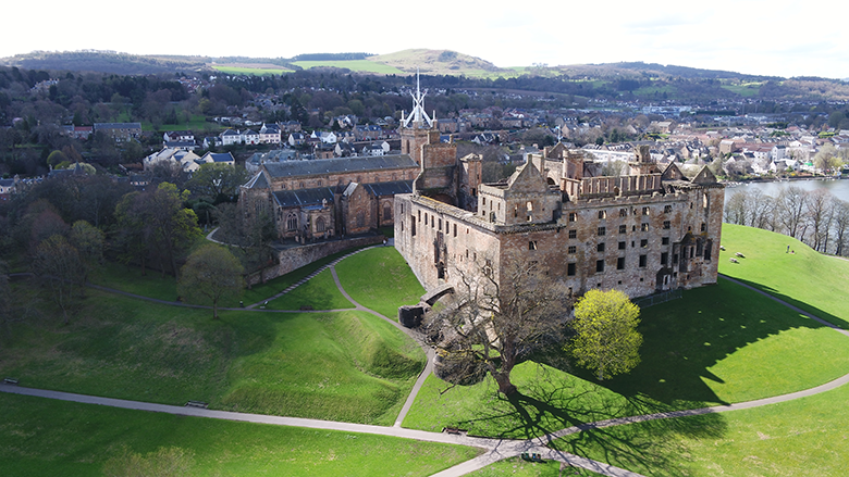 Aerial view of Linlithgow Palace, with green lawns and Linlithgow in the background