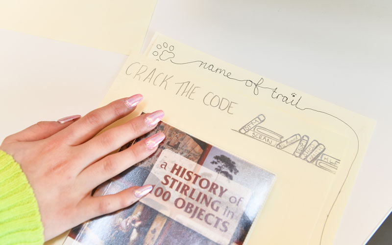Image of a young person's hand on top of a design for a new heritage trail in Stirling
