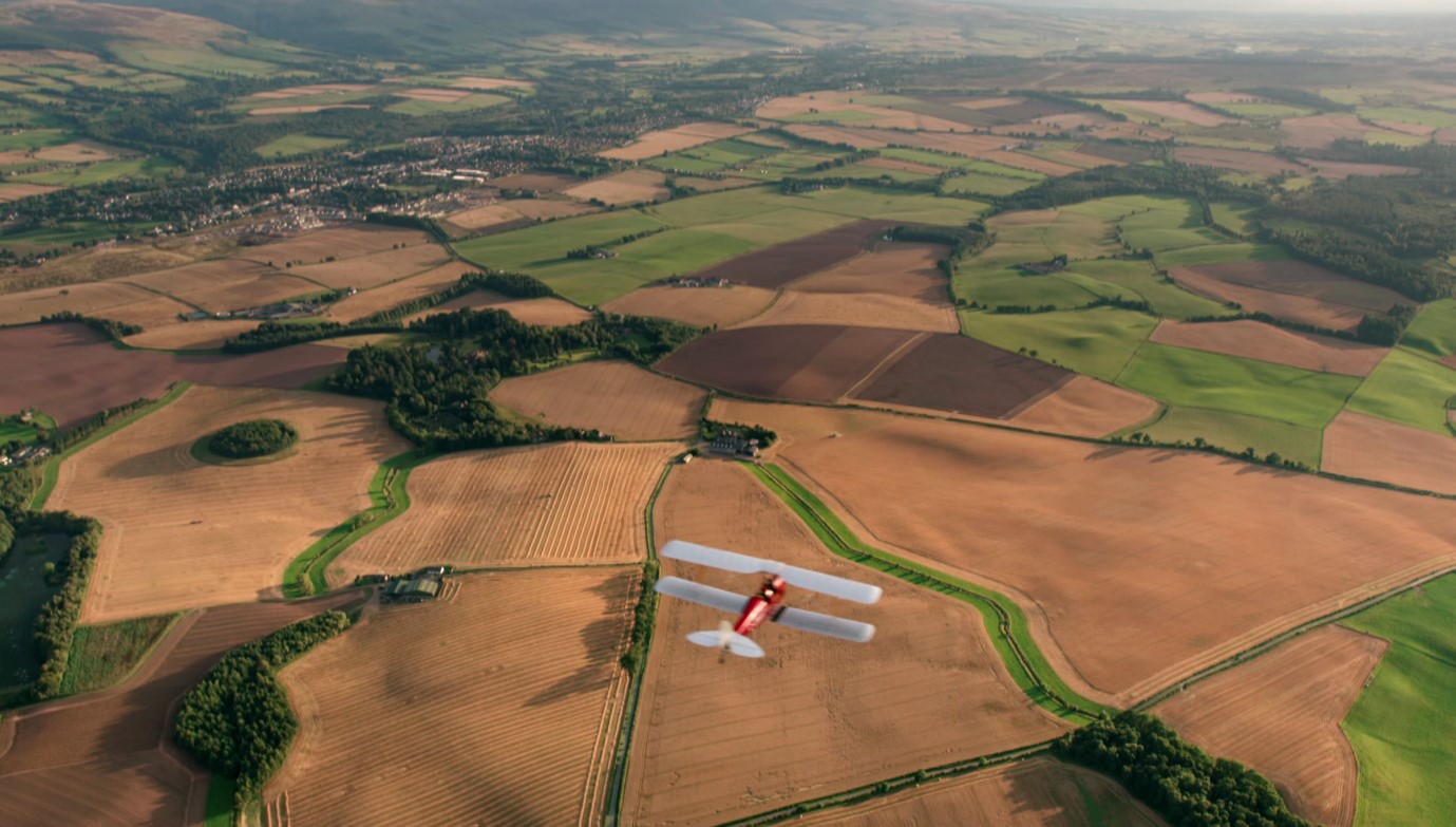 old fashioned plane flies over countryside