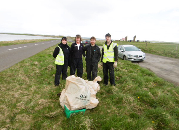 four people stand in a row in front of a plastic bag