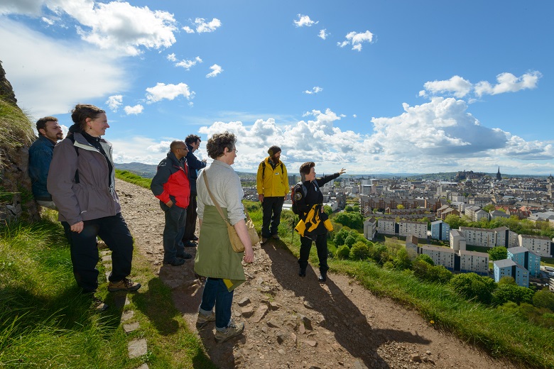 A ranger leads a tour of Arthur's Seat hill with great views of Edinburgh city in the background