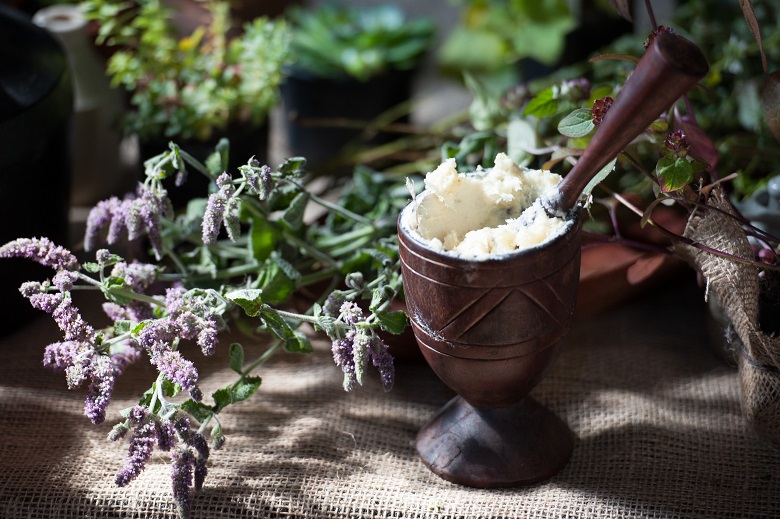 Close up of a herbalist's table with a mortar and pestle and some herbs and flowers