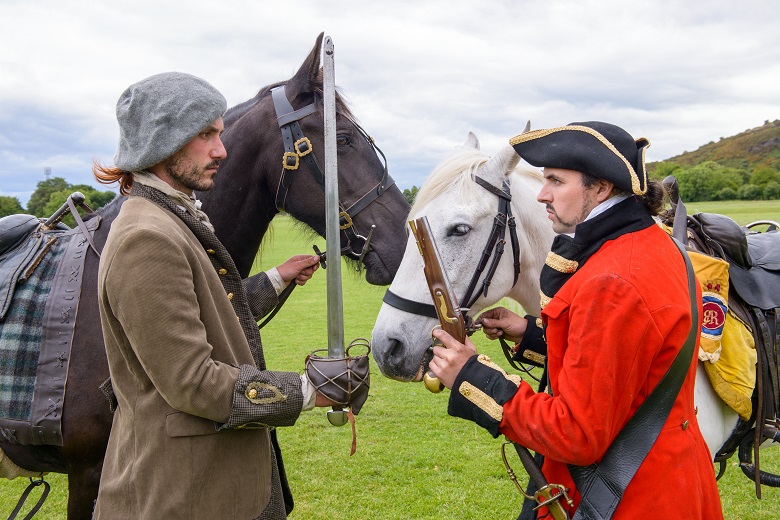 A redcoat and covenanter stand face to face, threatening each other in front of their horses