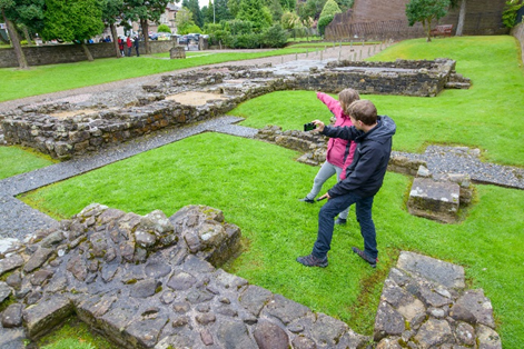 A man and a woman at the site of a Roman fort use apps on their phones
