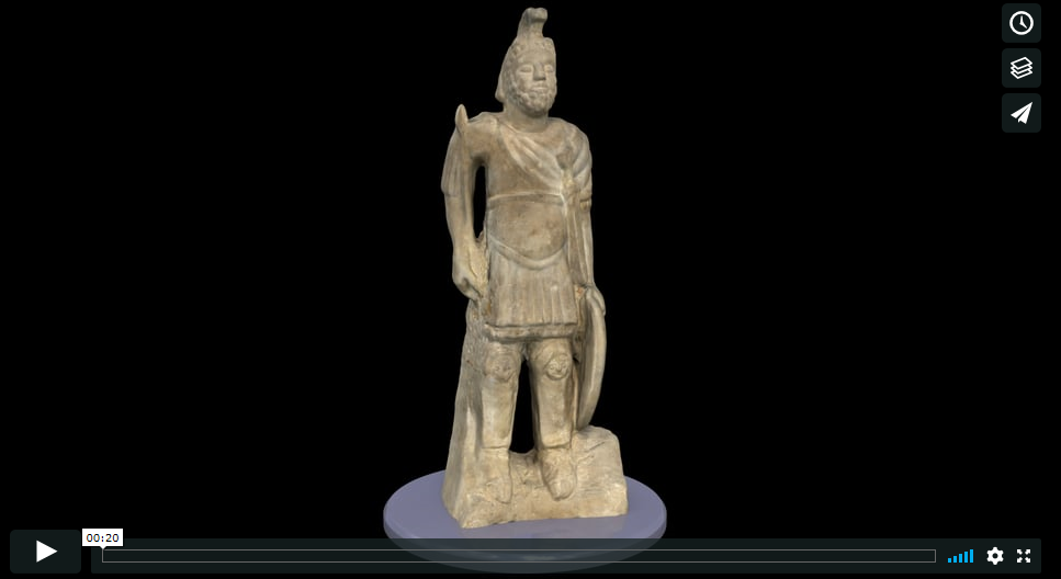 A stone statue of Mars, a Roman God. The statue is of a man wearing Roman-style military uniform. In one hand he holds a circular shield and in the other a sword. He wears a Roman helmet with a plume. 