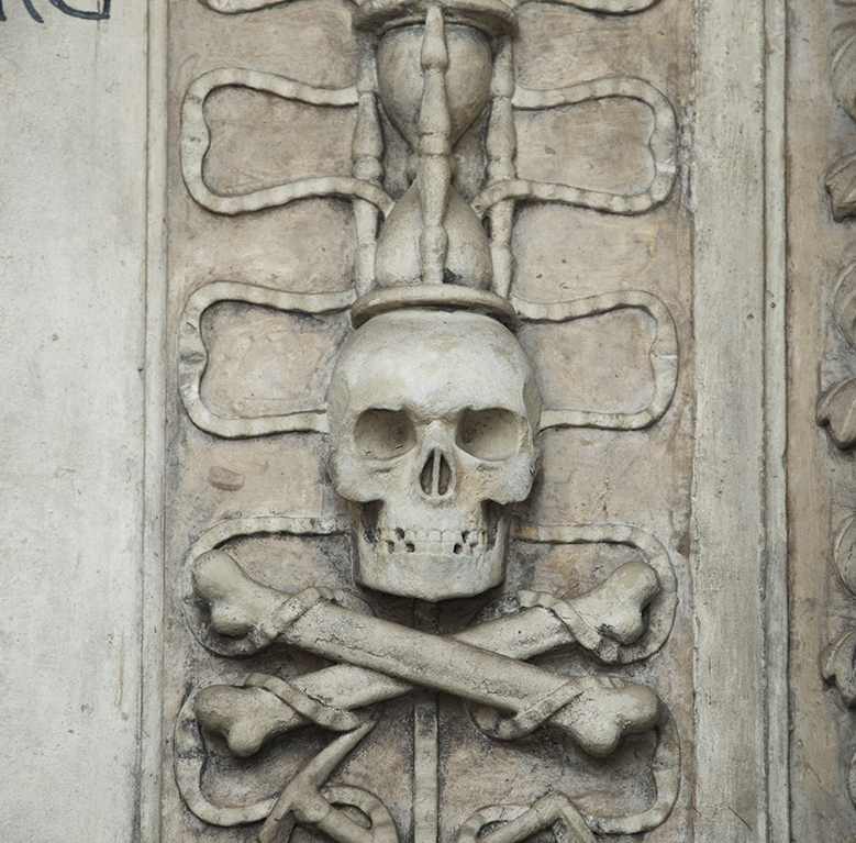 Carving of a skull and crossbones with an hour glass carved above it