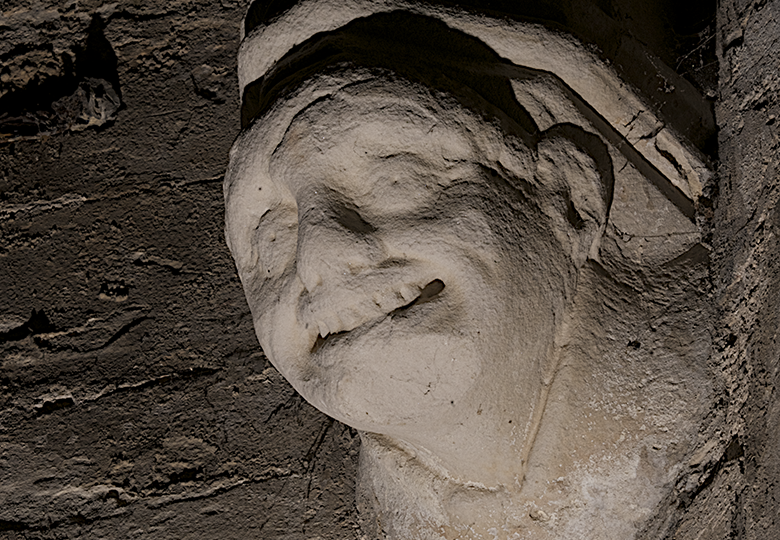 View from below of a spookily lit carving of a grimacing young man