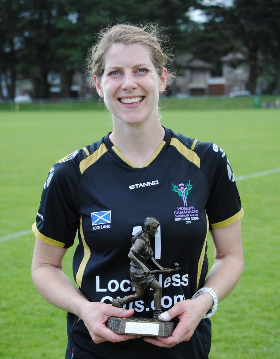 blonde woman smiles at camera as she holds a sports trophy