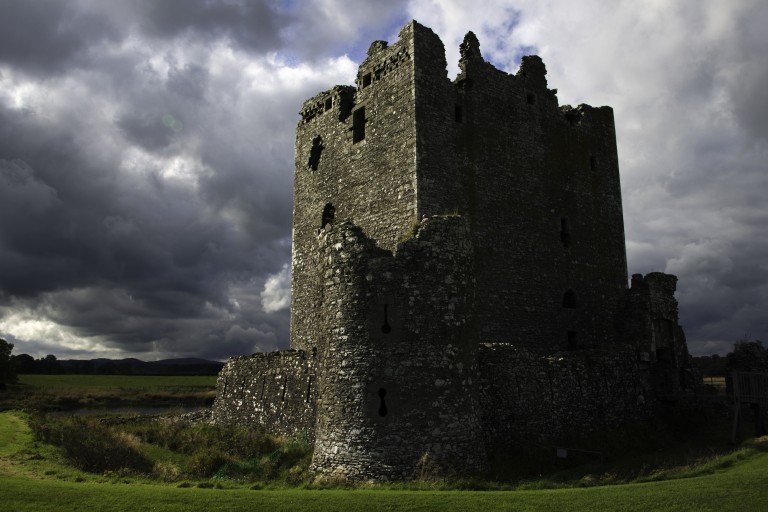 A foreboding castle tower with storm clouds in the sky above