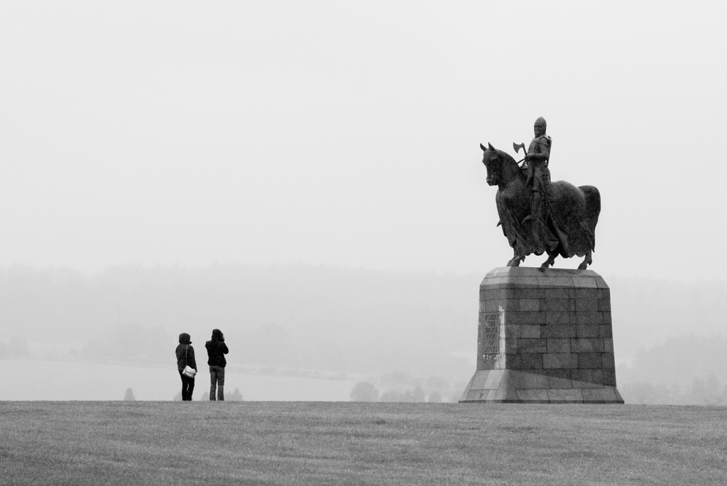 Two people with backs to camera look up at statue of man on horseback