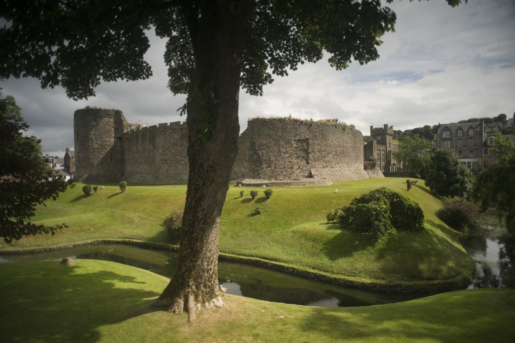 A castle with an imposing round wall, surrounded by a moat. 