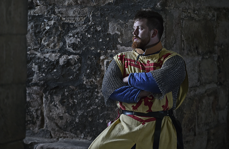 Man dressed as Robert the Bruce stares out of a castle window