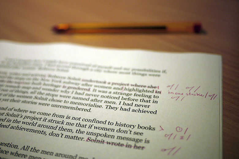 Close-up shot of a printed page being edited with red pen