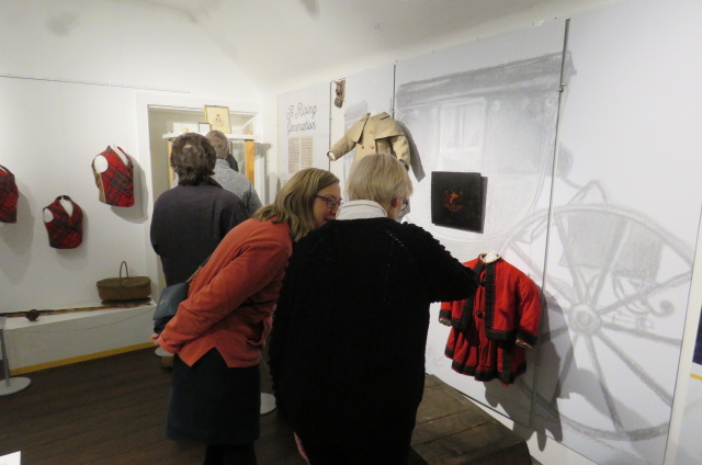 Visitors to the exhibition examine a display of Victorian clothing