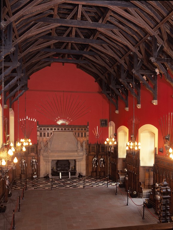 Interior view of the great hall at Edinburgh Castle. There is a distinctive timber roof and striking red walls. 