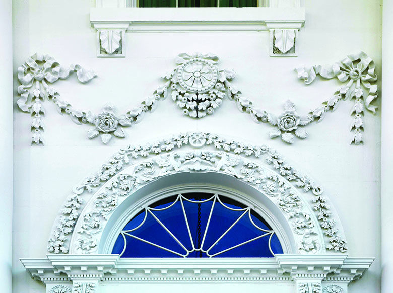 A close-up view of detailed stonework with complex floral designs above a doorway. 