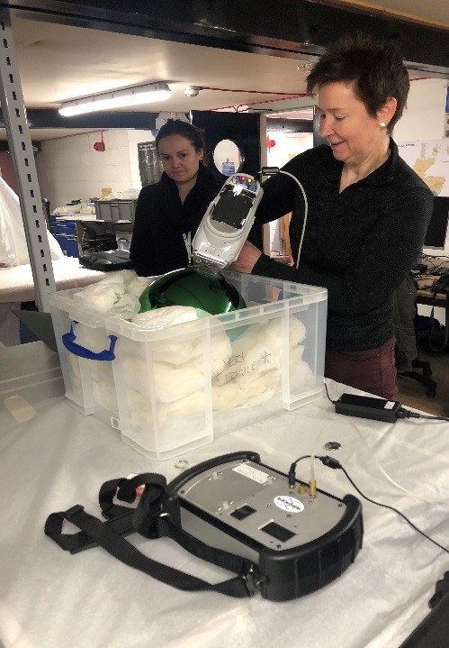 Women in a lab environment using a hand-held device to scan the witch's ball