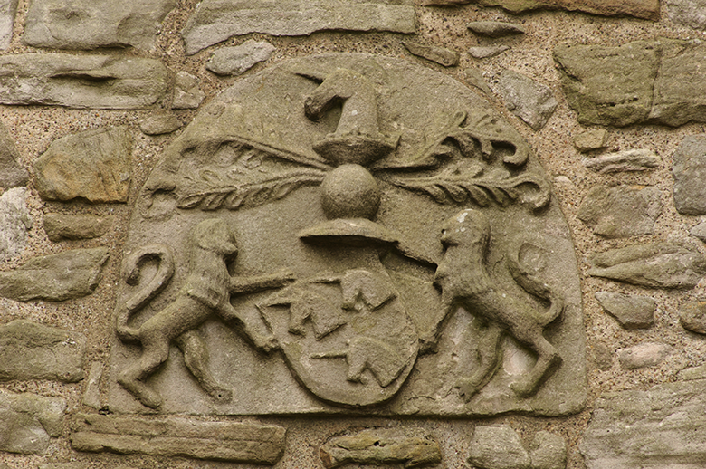 An ornate carving featuring a shield with three unicorn heads held by two lions