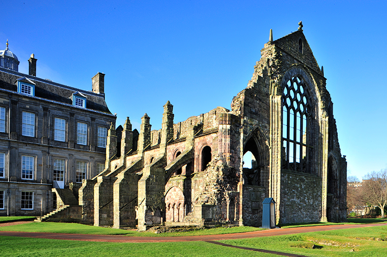 view of the ruined nave of Holyrood Abbey with the Palace of Holyroodhouse in the background 