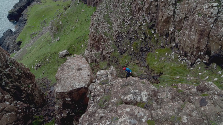 A man abseiling down a rocky cliff 