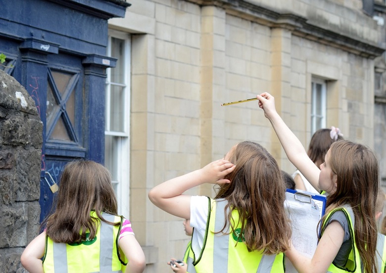 Youth club members wearing high viz jackets inspect a police call box on Canongate, Edinburgh